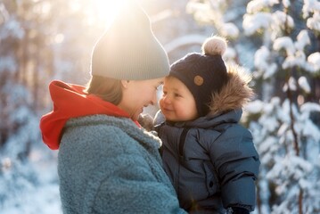 Young mother and her baby playing in the snowy forest. Young mother carrying her baby in the forest on a very snowy day.