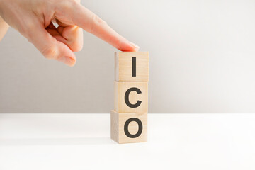 Female hand holding a cube, ICO letters on wooden cubes, business concept