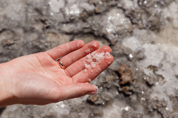 Natural frozen sea salt in the girl's hand. Backgrounds and texture on the seashore in stone deposits flooded with water and the remains of sea salt frozen in time. Close-up. Macro