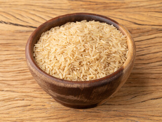 Raw brown whole rice in a bowl over wooden table