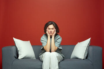 Young tired woman suffer headache closed eyes touching temples sitting on couch feeling exhausted by noisy neighbors