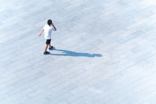 Top Of Aerial View Of Boy Walking At Pedestrian Walkway Outdoor For Traveling Or Exercise For Healthy. Funny Kid At Background Landscape Public Street In City.