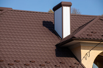 The roof of the house is made of red metal tiles, a beautiful large chimney