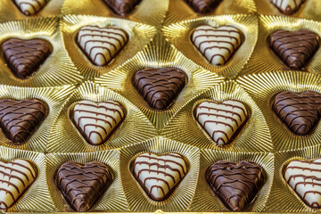 dark and white chocolate candies in the shape of hearts in a beautiful golden packaging