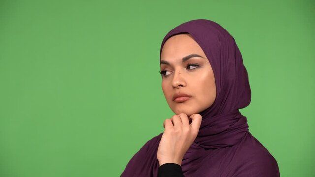 A young beautiful Muslim woman thinks about something - closeup - green screen background