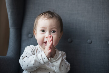 Portrait of a 1 year old baby with brown eyes and two teeth clapping