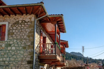 Fototapeta na wymiar Traditional 2-storey stone house with wooden balcony in Elati, a mountainous village in the Trikala Prefecture, Greece. Elati is a popular tourist destination and resort during the whole year.