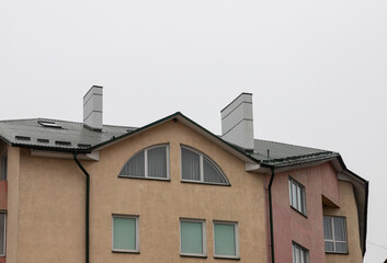 The roof of the house is made of red metal tiles, a beautiful large chimney