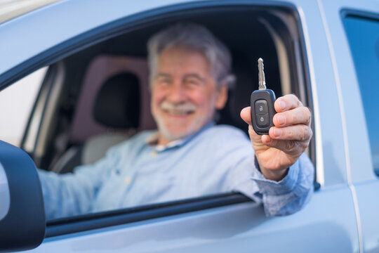Portrait of happy old man showing keys of car to the camera. Satisfied customer enjoying his new car..