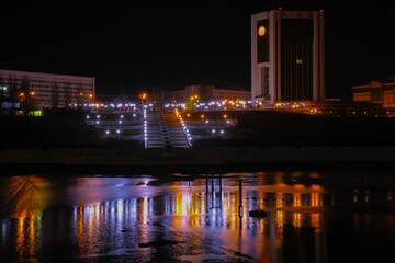 House of the Government of the Chuvash Republic on the shore of the bay at night, with reflections in the water.