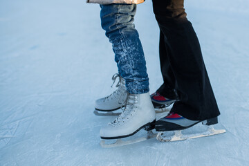 two girls in figure skates skate on an open skating rink in winter, winter entertainment and...
