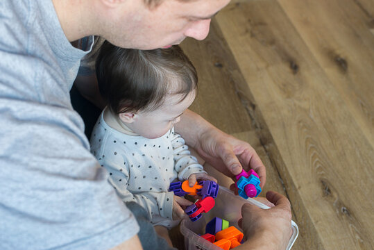 Baby playing with dad in a colored constructor sitting on the floor
