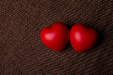 two large red hearts on a textile background close up
