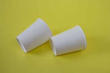 Two white paper cups on a yellow background