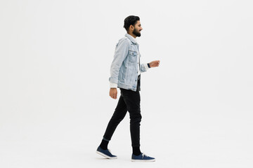 Full length side shot of handsome beard man smiling and walking, isolated on white background
