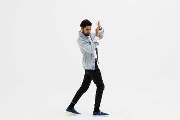 Young indian man standing scared over white studio background.