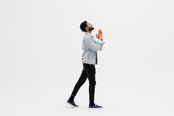 Young indian man look up and pray over white background