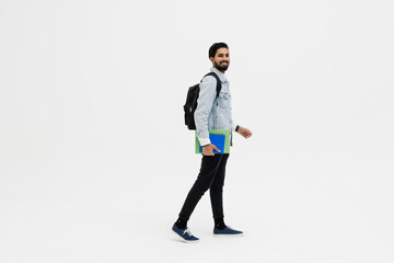 Young student indian man smiling, looking at camera and holding books walk isolated on white background