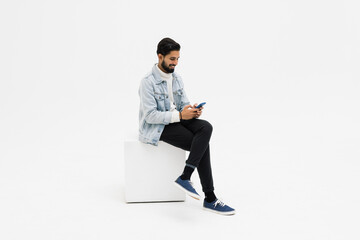 Young man sitting on chair while looking at phone celebrating on white background - Powered by Adobe