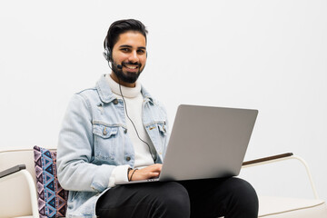 technology, leisure and people concept - happy man in wireless headphones with laptop at home