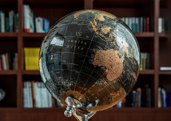 Chiang Rai,Thailand - Sep 06, 2020 : Replica globe on the background of bookshelves in library. Selective focus. - Powered by Adobe