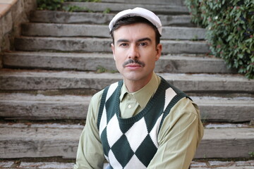 Man with a mustache wearing sleeveless rhombus sweater