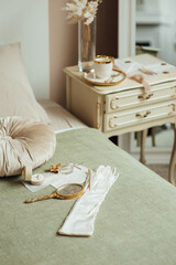 Vintage accessories on the bed and bedside table. Boho style. Gloves, cup and mirror