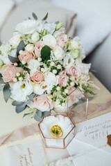 Beautiful wedding bouquet and rings of the newlyweds near the invitation cards. Boho style