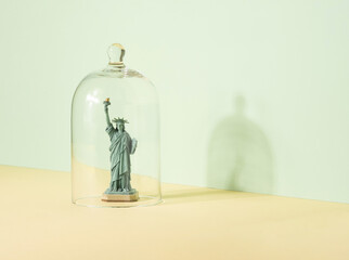 Statue of liberty figurine under the glass bell. United States isolation minimal concept.