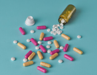 White tablets and yellow and pink capsules are scattered.