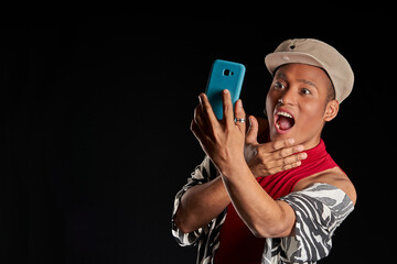 Latin man making video call looking in amazement at his cell phone