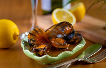 Steamed mussels on a wooden table with lemons and a glass of wine.