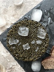 black caviar in round jar surrounded by ice cubes. Sturgeon fish eggs