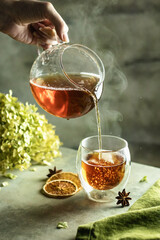 Tea brewing process. A cup of freshly sourced tea with bubbles and steam on textured background