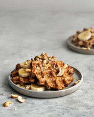 Delicious oat waffles with banana and nuts on gray background