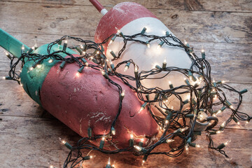 Fototapeta na wymiar Colorful Maine Red green and white lobster float buoys surrounded by Christmas holiday lights