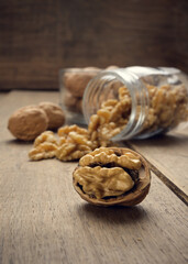 Nuts coming out of a glass jar on a wooden table in a dark environment.. High quality photo