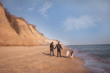 a couple of lovers are walking along the seashore with dogs, love story