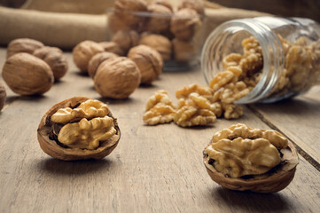 Nuts coming out of a glass jar on a wooden table in a dark environment.. High quality photo