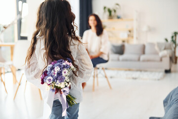 Giving parent flowers. Mother and her daughter spending time together at home