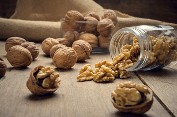 Nuts coming out of a glass jar on a wooden table in a dark environment.. High quality photo