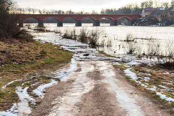 Close up view of ice drift on the frozen river. Melting ice. Flooded road. Old bridge. Concept of...