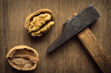 Walnut cracked by an old hammer in a dark environment on wooden table. High quality photo