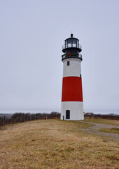 Fototapeta na wymiar The Sankaty Head Coast Guard Lighthouse on the island of Nantucket on a drizzly and foggy day