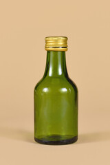 Single empty green glass bottle on beige background
