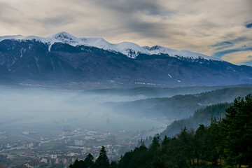 Pirin mountain, Bulgaria. Covered in snow peak in winter skiing season. Mist fog and Razgrad city below the mountain