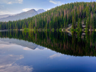 Pine trees and mountains reflected in the calm waters of Bear lake in Rocky Mountain National Park Colorado