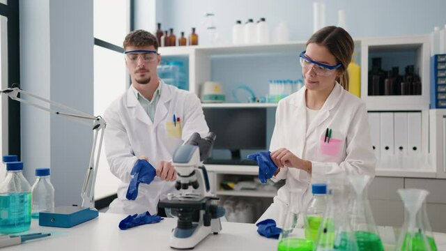 Young couple wearing scientist uniform and gloves at laboratory