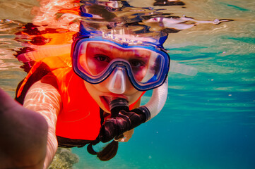 a girl in a life jacket and a mask with a snorkel under water