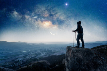 silhouette of a hiker on the top of the mountain staring the Milky Way and the Moon over Valle del Elqui